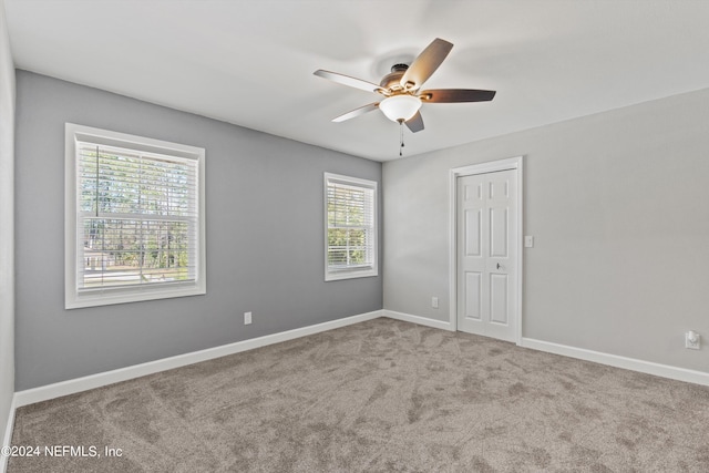 empty room with ceiling fan and light carpet