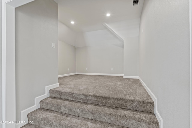 stairway featuring vaulted ceiling and carpet floors