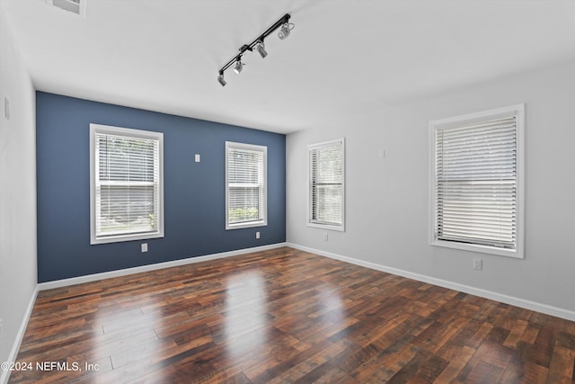 unfurnished room featuring rail lighting and dark hardwood / wood-style floors