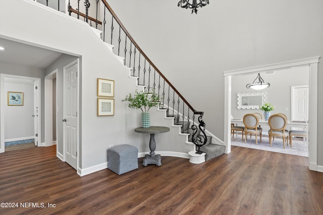 entryway featuring dark wood-type flooring, a chandelier, and a high ceiling