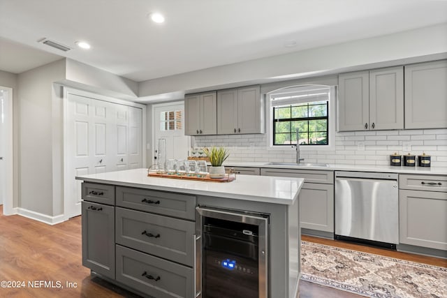 kitchen featuring beverage cooler, sink, dishwasher, gray cabinetry, and light hardwood / wood-style flooring