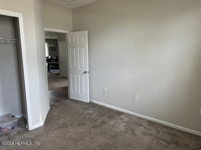 unfurnished bedroom with a closet and dark carpet