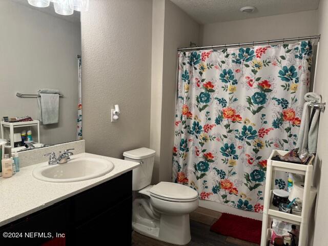 bathroom with toilet, vanity, hardwood / wood-style flooring, a textured ceiling, and curtained shower