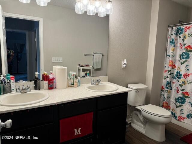 bathroom with wood-type flooring, toilet, vanity, and a shower with curtain