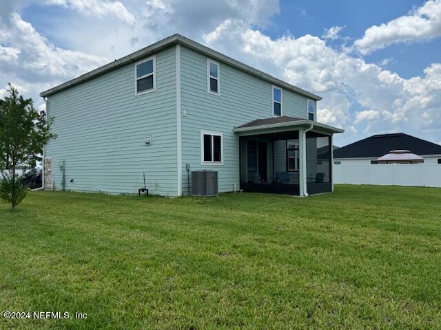 rear view of house with a sunroom, cooling unit, and a yard