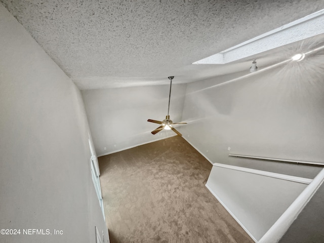 interior space featuring lofted ceiling with skylight, carpet flooring, and ceiling fan