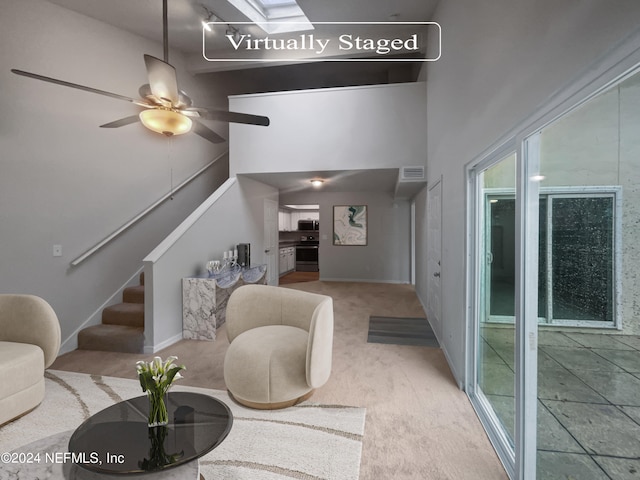 living room featuring a high ceiling, light carpet, and ceiling fan