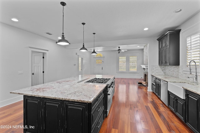 kitchen with stainless steel dishwasher, pendant lighting, wood-type flooring, backsplash, and a center island