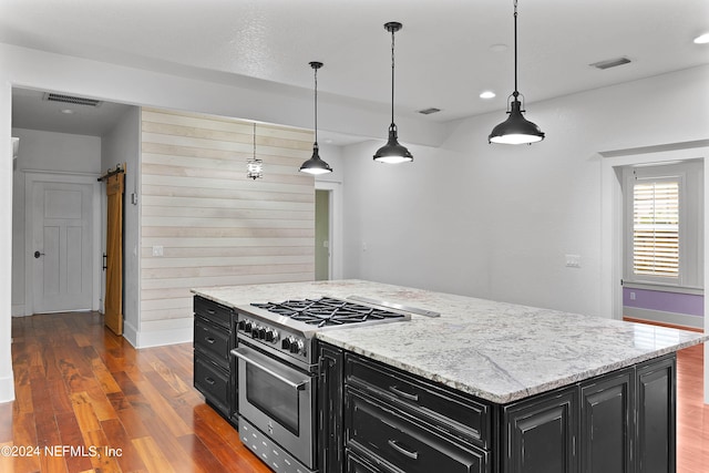 kitchen with a barn door, a center island, hardwood / wood-style flooring, and pendant lighting