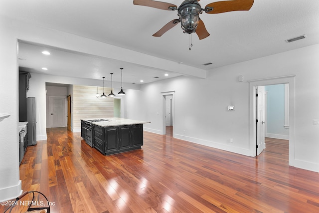 kitchen featuring ceiling fan, wood-type flooring, a kitchen island, hanging light fixtures, and appliances with stainless steel finishes