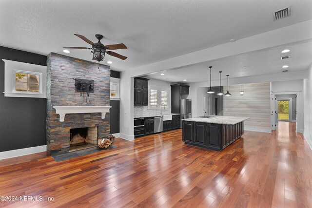 living room featuring hardwood / wood-style floors, a textured ceiling, ceiling fan, and a fireplace