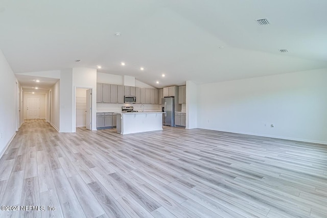 unfurnished living room featuring vaulted ceiling, sink, and light wood-type flooring