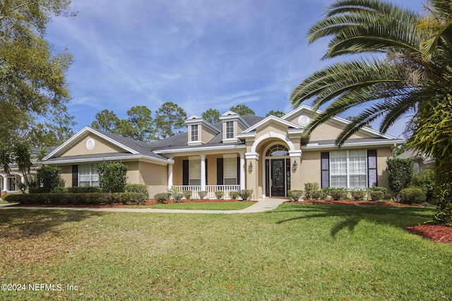 view of front of property featuring covered porch, stucco siding, and a front yard