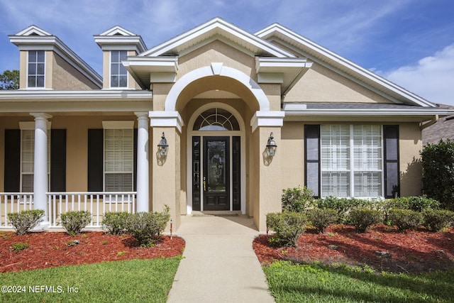 view of exterior entry featuring stucco siding and a porch