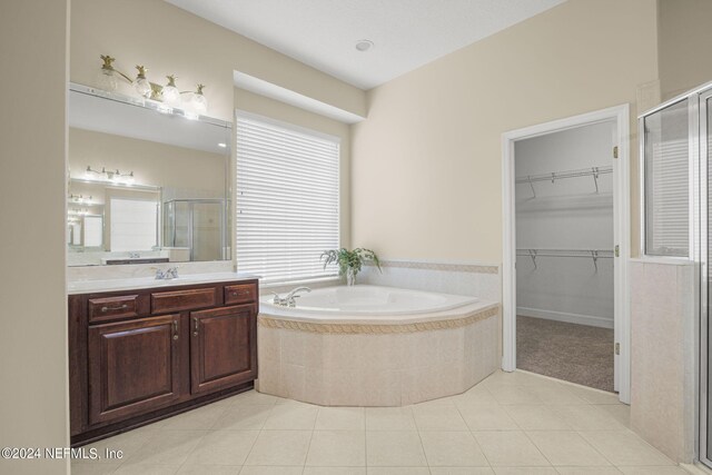 bathroom with a spacious closet, a shower stall, a garden tub, tile patterned floors, and vanity