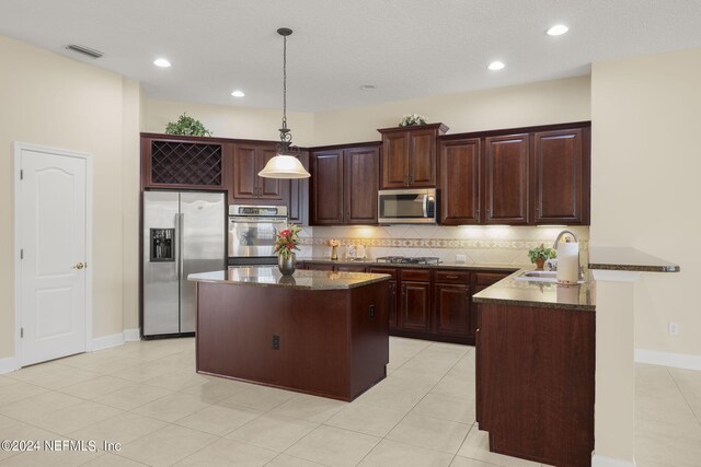 kitchen with visible vents, a sink, appliances with stainless steel finishes, a peninsula, and decorative backsplash