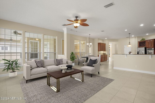 living area featuring visible vents, baseboards, light tile patterned floors, ceiling fan with notable chandelier, and recessed lighting