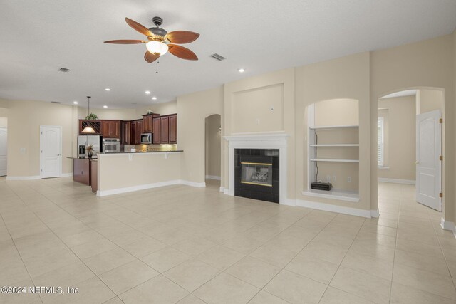 unfurnished living room with built in features, recessed lighting, a tile fireplace, and baseboards