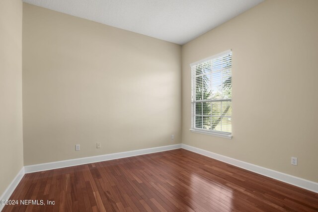 spare room with dark wood finished floors and baseboards