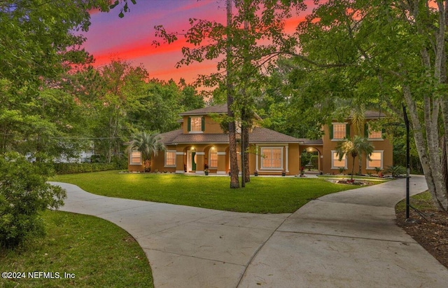 view of front of property featuring stucco siding, concrete driveway, and a yard