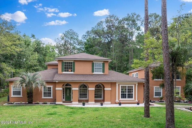 view of front of house featuring a shingled roof, a front yard, and stucco siding