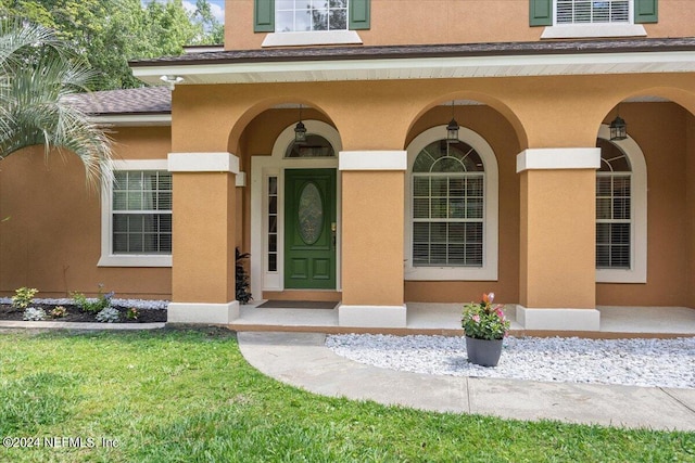 entrance to property with roof with shingles and stucco siding