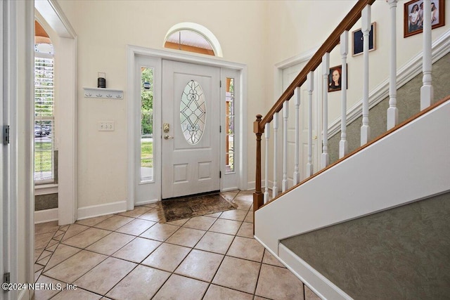 foyer entrance with a wealth of natural light, stairway, baseboards, and light tile patterned floors