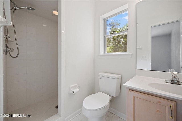 full bathroom featuring baseboards, a tile shower, vanity, and toilet