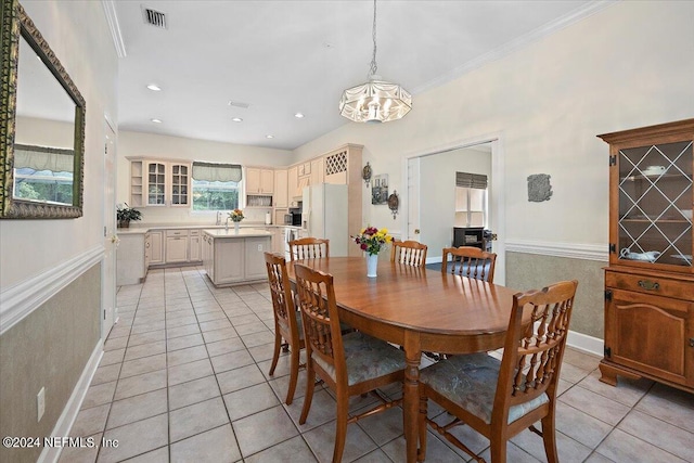 dining area featuring light tile patterned floors, a notable chandelier, visible vents, and crown molding