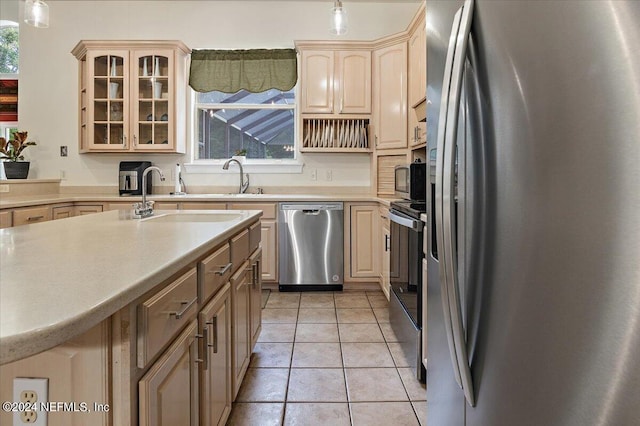 kitchen with light tile patterned floors, stainless steel appliances, light countertops, glass insert cabinets, and a sink