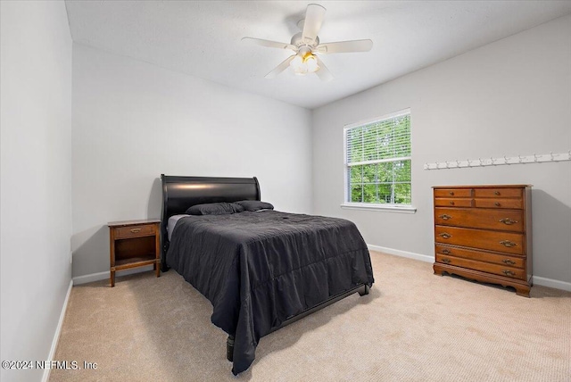 bedroom with a ceiling fan, light colored carpet, and baseboards