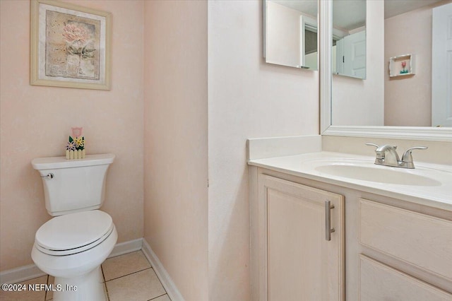 half bathroom featuring tile patterned flooring, baseboards, vanity, and toilet