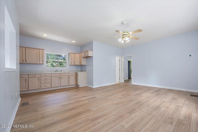 kitchen featuring baseboards, ceiling fan, light countertops, light wood-style floors, and a sink