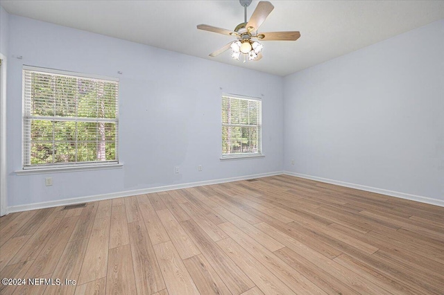 spare room featuring light wood-style floors, visible vents, baseboards, and a ceiling fan