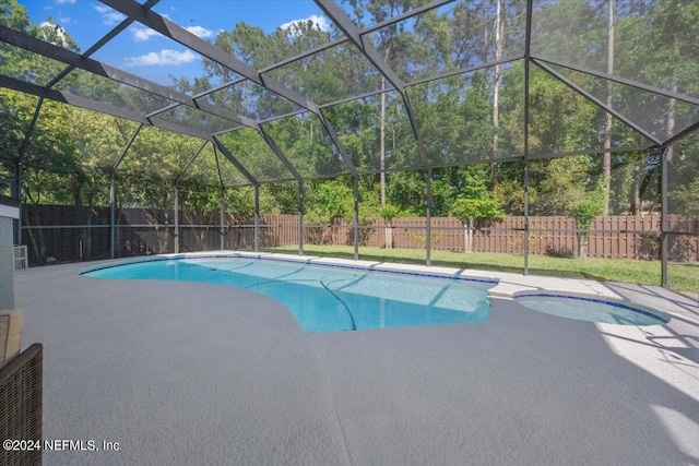 view of swimming pool featuring a patio, a fenced backyard, a pool with connected hot tub, and a lanai