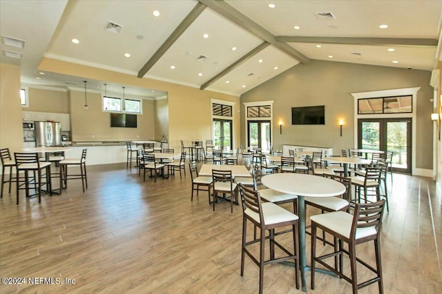 dining space featuring beamed ceiling, high vaulted ceiling, light hardwood / wood-style flooring, and a healthy amount of sunlight