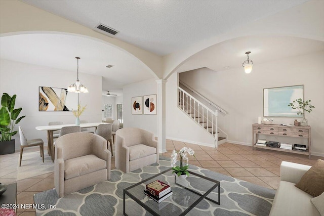 tiled living room featuring ceiling fan with notable chandelier