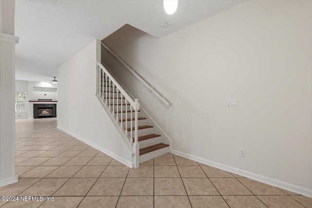 stairway featuring tile patterned floors, ceiling fan, and a textured ceiling