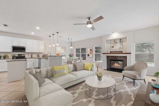 tiled living room featuring ceiling fan, sink, and a textured ceiling