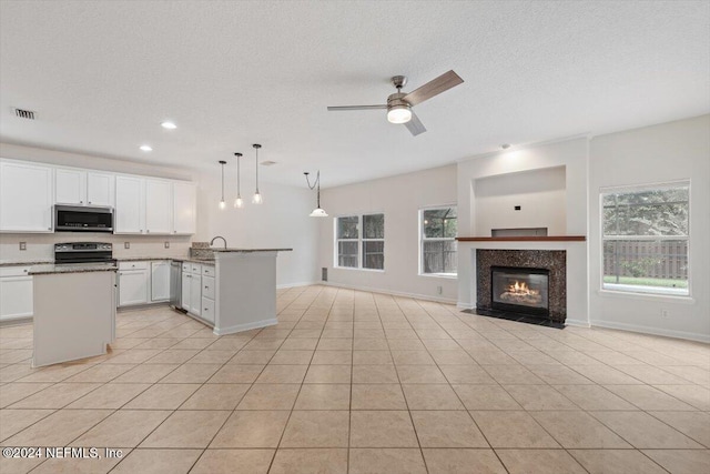 kitchen with black stove, ceiling fan, pendant lighting, light tile patterned floors, and white cabinetry