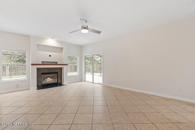 unfurnished living room featuring light tile patterned floors, a textured ceiling, plenty of natural light, and ceiling fan