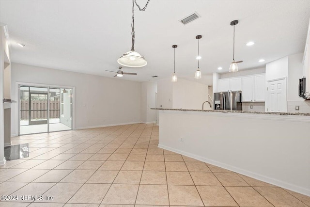 kitchen featuring white cabinetry, ceiling fan, light stone countertops, stainless steel fridge, and light tile patterned floors