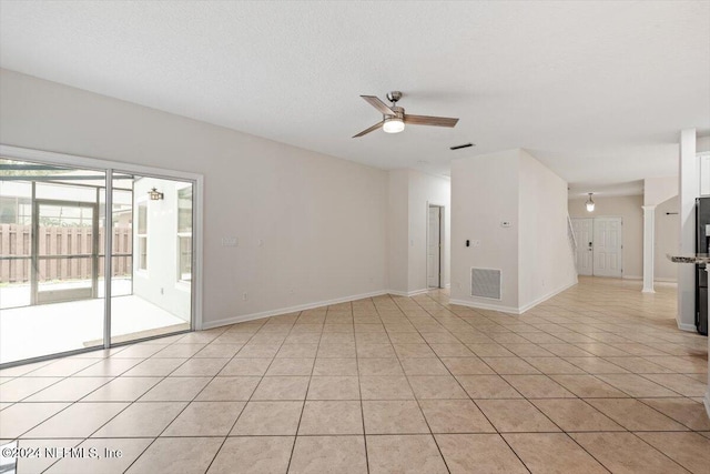 empty room with ceiling fan, light tile patterned floors, and a textured ceiling