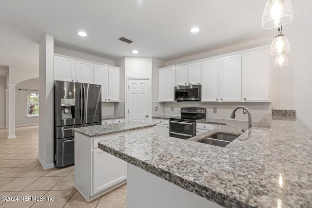 kitchen with stainless steel appliances, sink, light tile patterned floors, white cabinetry, and hanging light fixtures