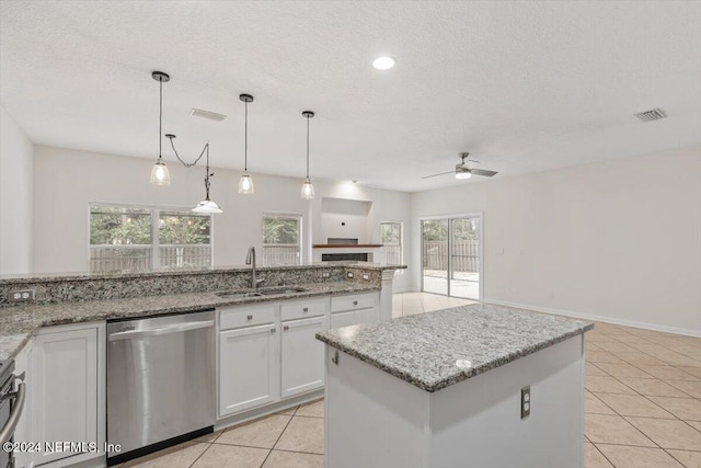 kitchen featuring ceiling fan, dishwasher, white cabinets, and a center island with sink