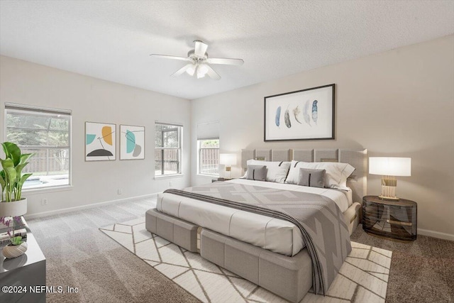 bedroom featuring ceiling fan, light colored carpet, and a textured ceiling