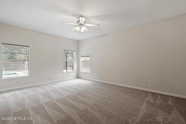 carpeted empty room with ceiling fan and a textured ceiling