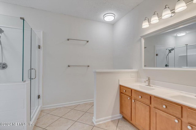 bathroom featuring tile patterned flooring, vanity, a shower with door, and a textured ceiling