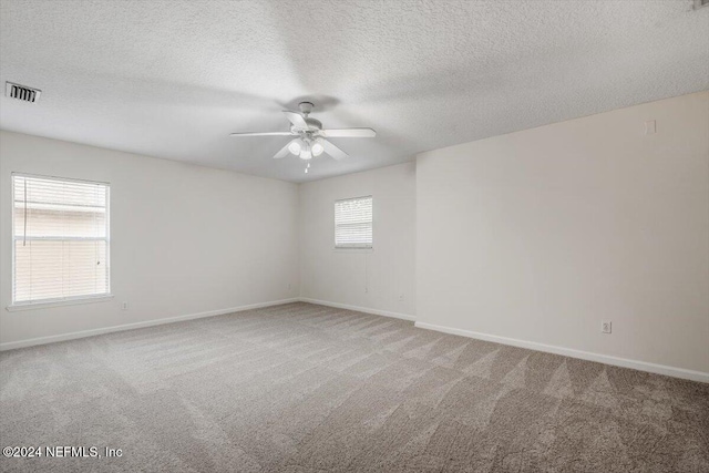 carpeted spare room with a textured ceiling and ceiling fan