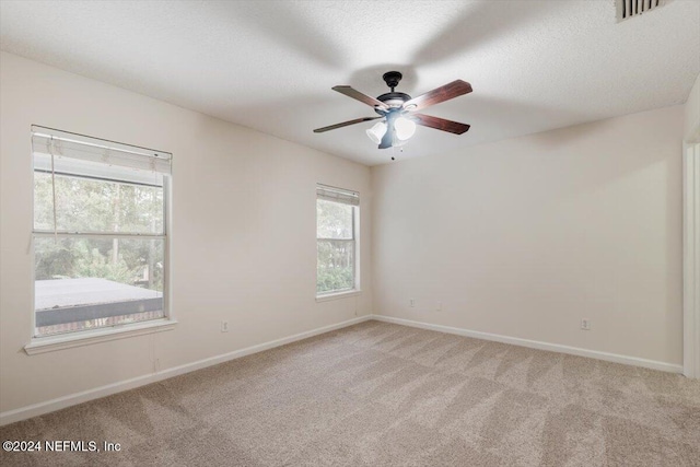 carpeted spare room featuring ceiling fan and a textured ceiling